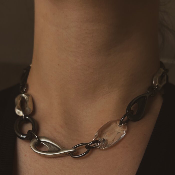 Modernus vėrinys su Swarovski kristalu ir hematitu - subtilus, bet išraiškingas stiliaus akcentas. Skirtingų formų metalinės jungtys kuria šiuolaikišką, dinamišką dizainą, o skaidrus Swarovski kristalas suteikia lengvo spindesio ir elegancijos. Puikiai tinka tiek kasdieniam įvaizdžiui, tiek ypatingoms progoms.